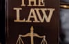 The Scales of Justice on a dark colored book titled The Law.